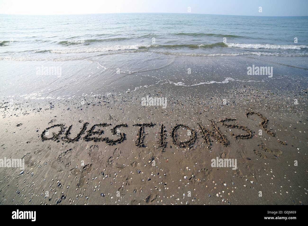 Wort-Fragen geschrieben in großen Lettern auf dem Sand des Meeres Stockfoto
