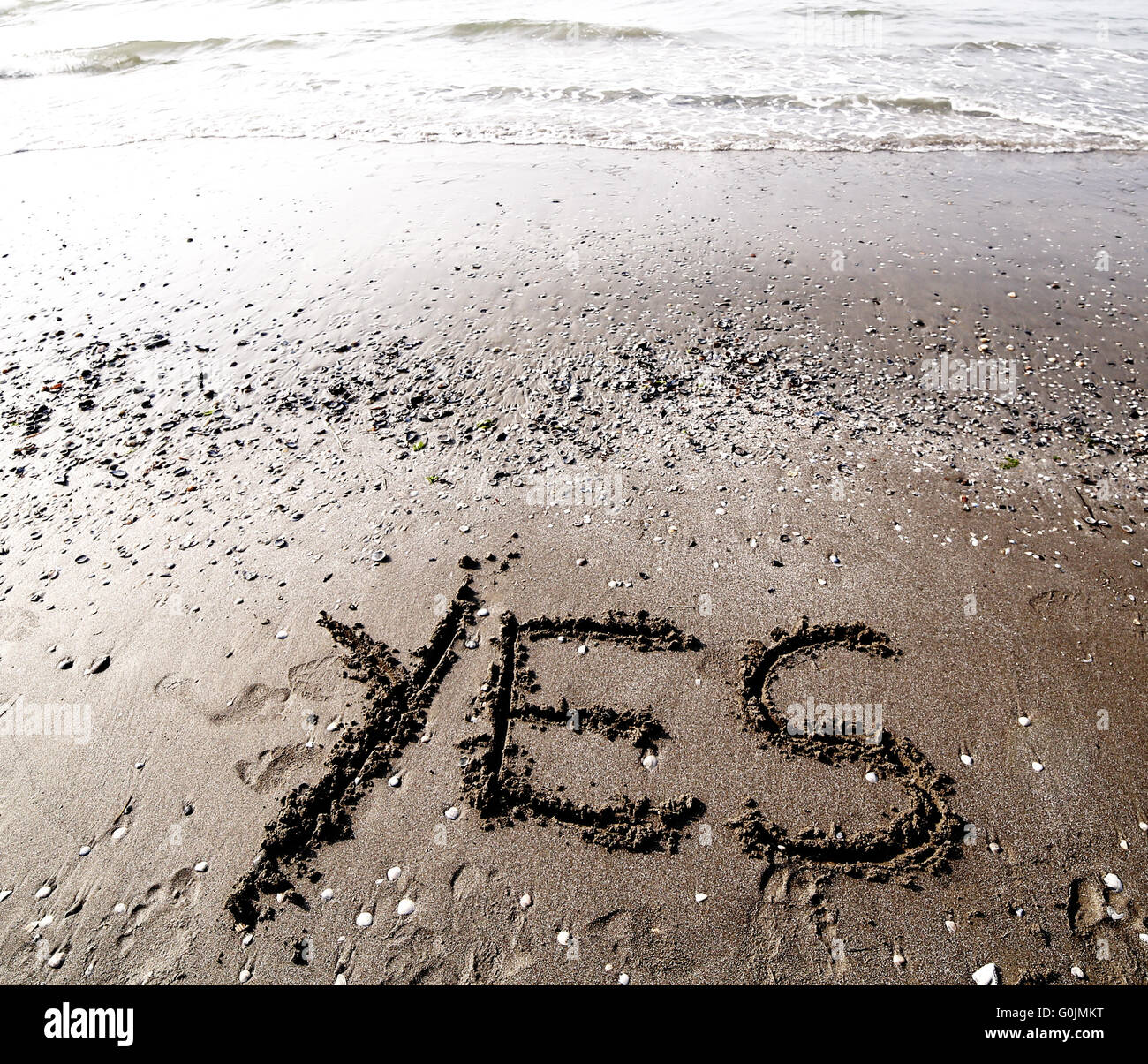 Große Schrift auf dem Sand des Meeres mit dem Wort ja Stockfoto