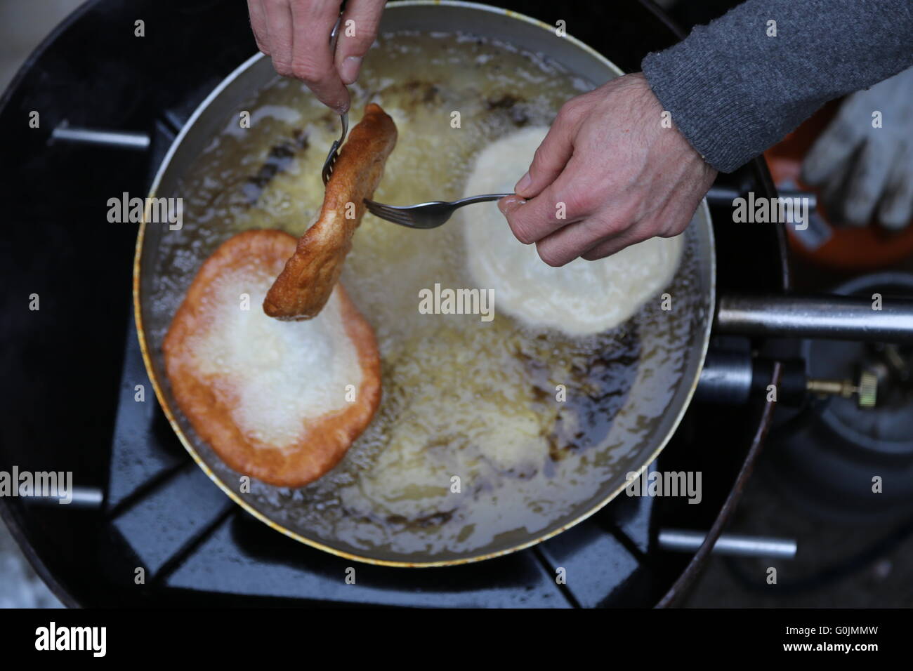 Cook Hände sammeln die Pfannkuchen aus dem Öl kochen in der Stadt Straße Stockfoto