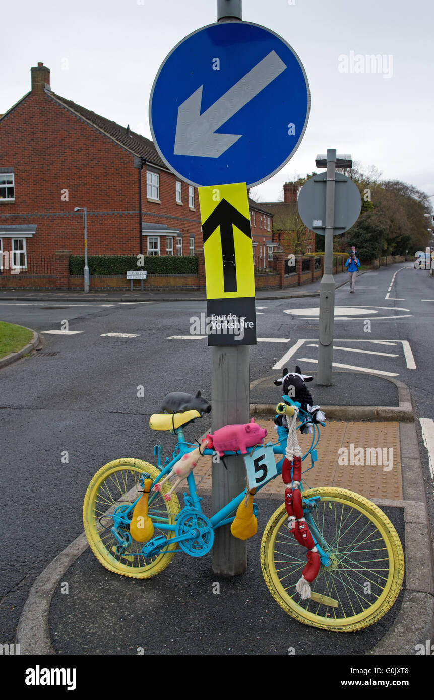 Great Ayton, North Yorkshire UK, 1. Mai 2016. Ein Fahrrad bemalt und dekoriert mit sortierten Tiere und andere Symbole der Landwirtschaft, an einem Poller an einer Straßenkreuzung im Dorf, auf der Route der Radsport Tour de Yorkshire. 3. Etappe führt durch das Dorf heute. Stockfoto