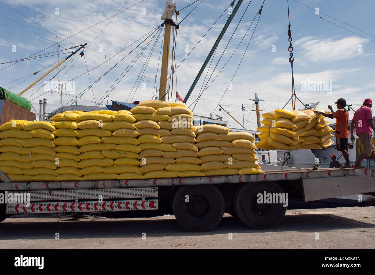 Arbeiter geladen Säcke Zement in den Rumpf eines Bootes im Hafen Paotere in Makassar, Indonesien. Stockfoto