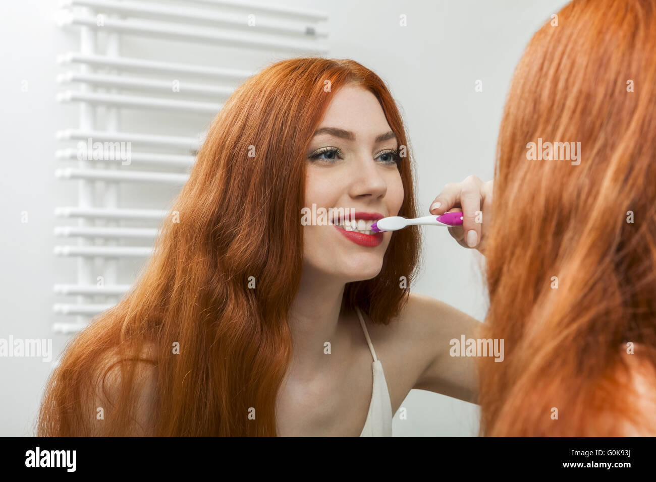 Frau vor einem Spiegel ihre Zähne putzen Stockfoto