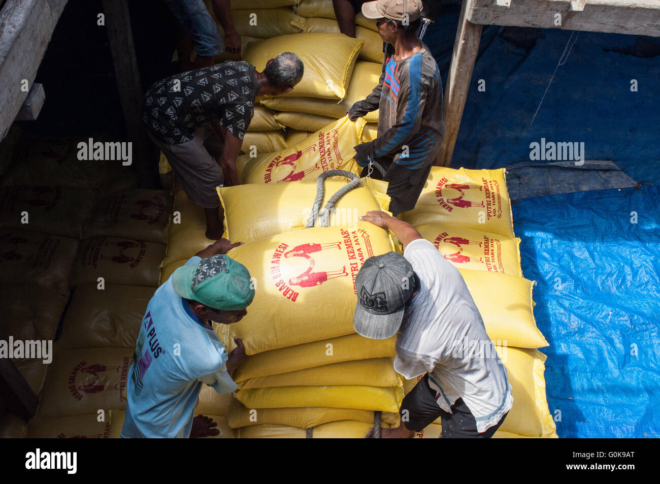Arbeiter geladen Säcke Zement in den Rumpf eines Bootes im Hafen Paotere in Makassar, Indonesien. Stockfoto