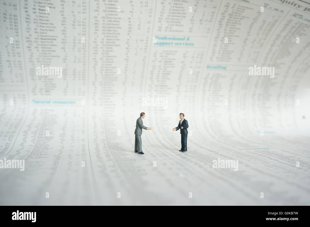 Miniatur-Geschäftsleute stehen auf der Seite "Shares" einer Zeitung Stockfoto