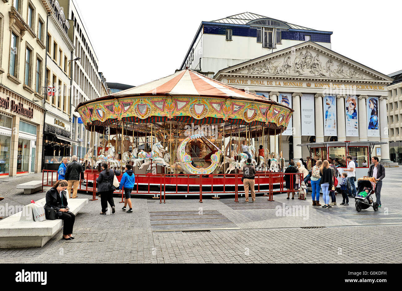 Einige Leute genießen einen schönen Tag im September um ein Karussell installiert vor dem Königlichen Theater la Monnaie in Brüssel. Stockfoto
