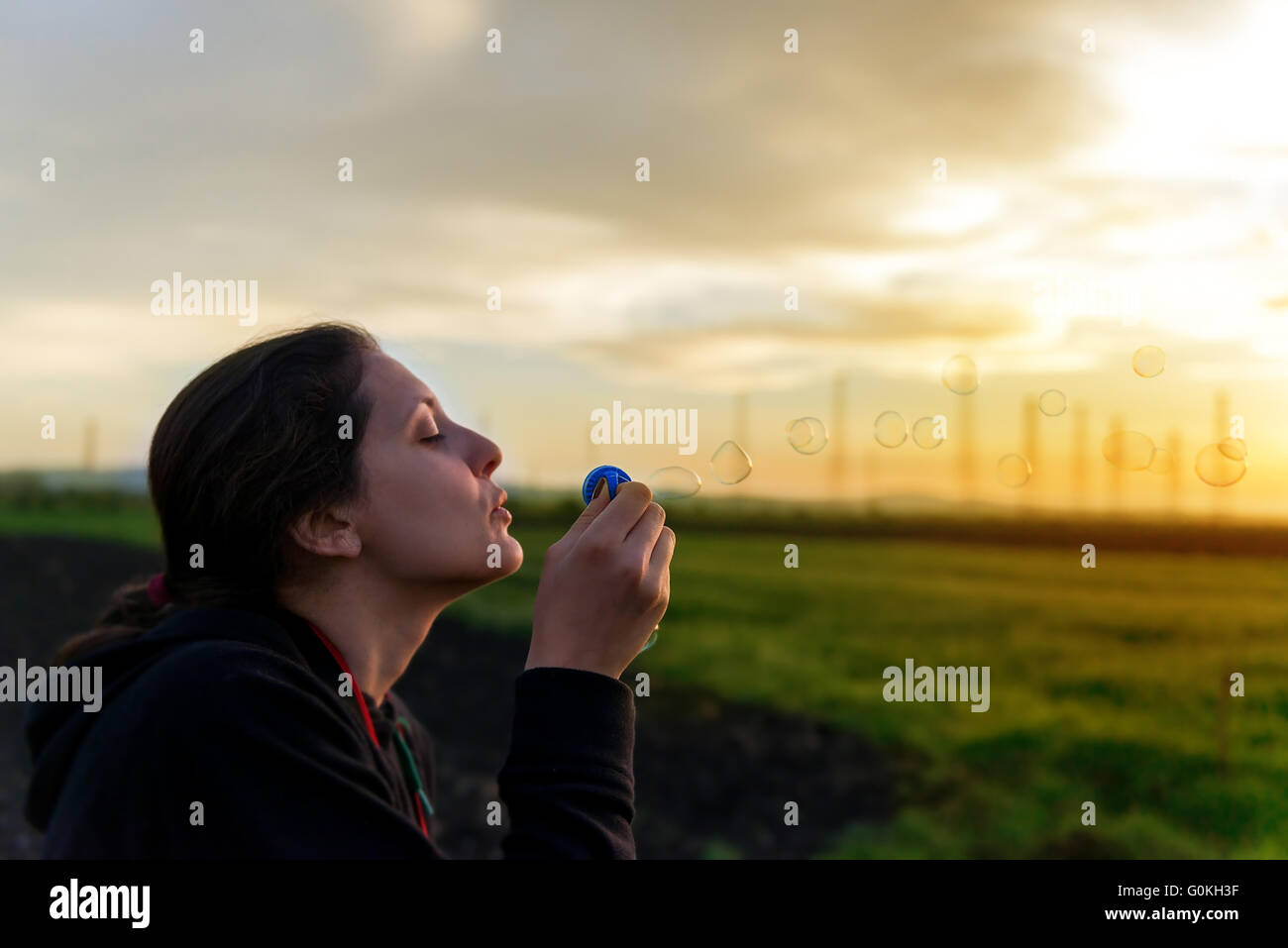 Portrait der schönen Frau bläst Seifenblasen im Feld Stockfoto
