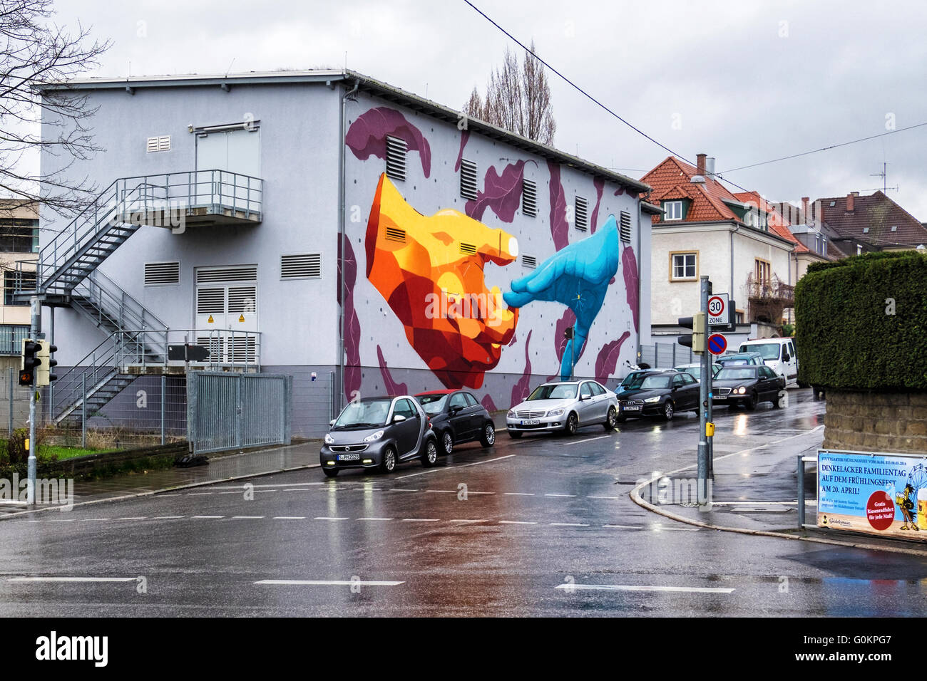 Stuttgart, Deutschland. Riesige Wandmalerei Streetart. Zwei ausgestreckten Händen und fallende lila Blätter auf Seite des Gebäudes Stockfoto