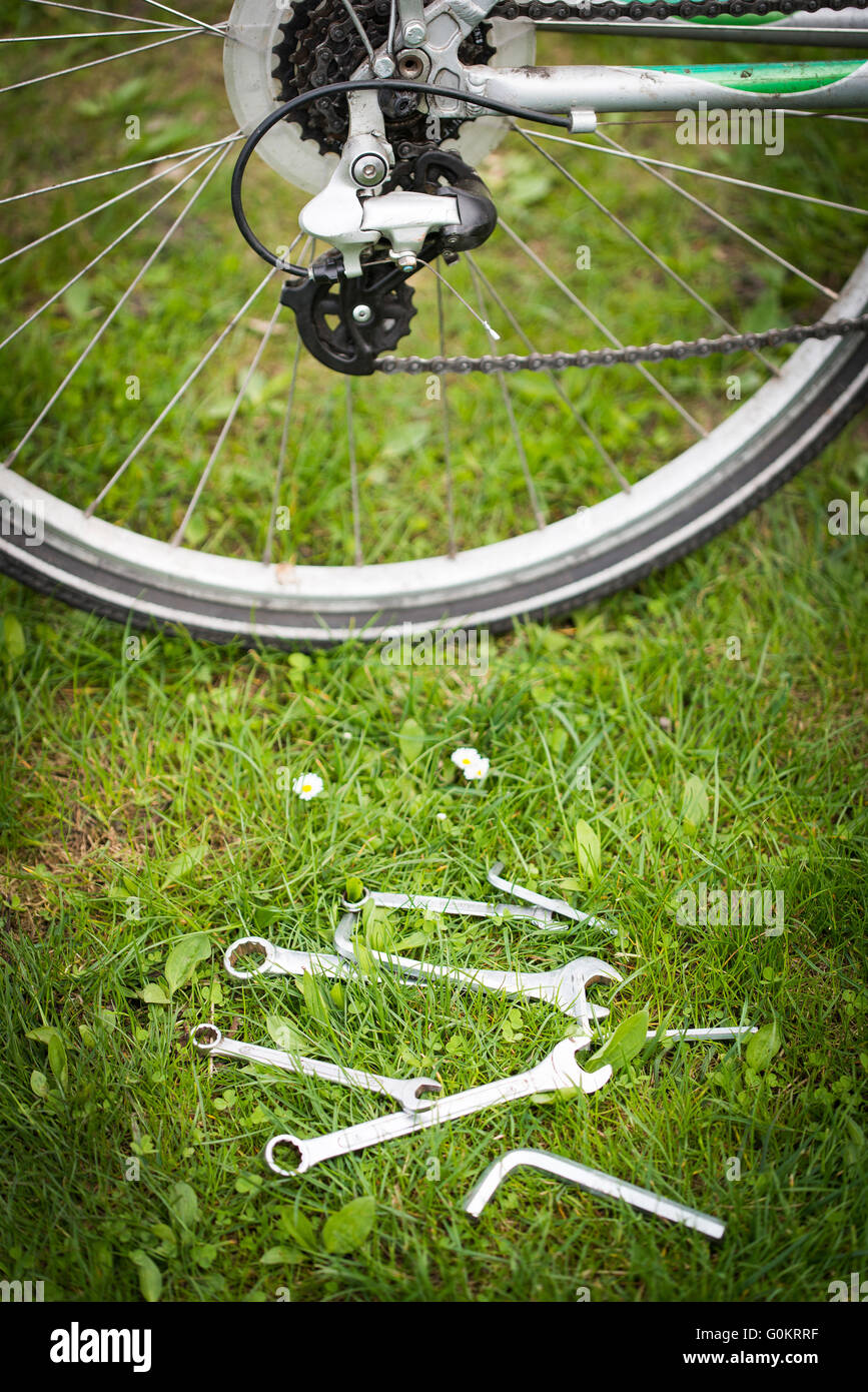 eingestellt von Schlüsseln, das Fahrrad auf dem Rasen liegend zu reparieren. Stockfoto