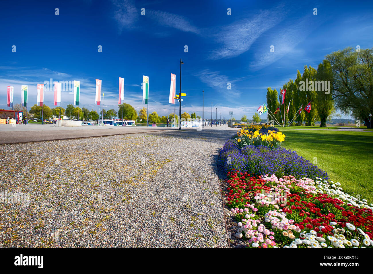 Fahnen und Blumen entlang Uhrim in Kreuzlingen Stadtzentrum in der Nähe von Konstanz Stadt mit dem Bodensee und Boot. Stockfoto