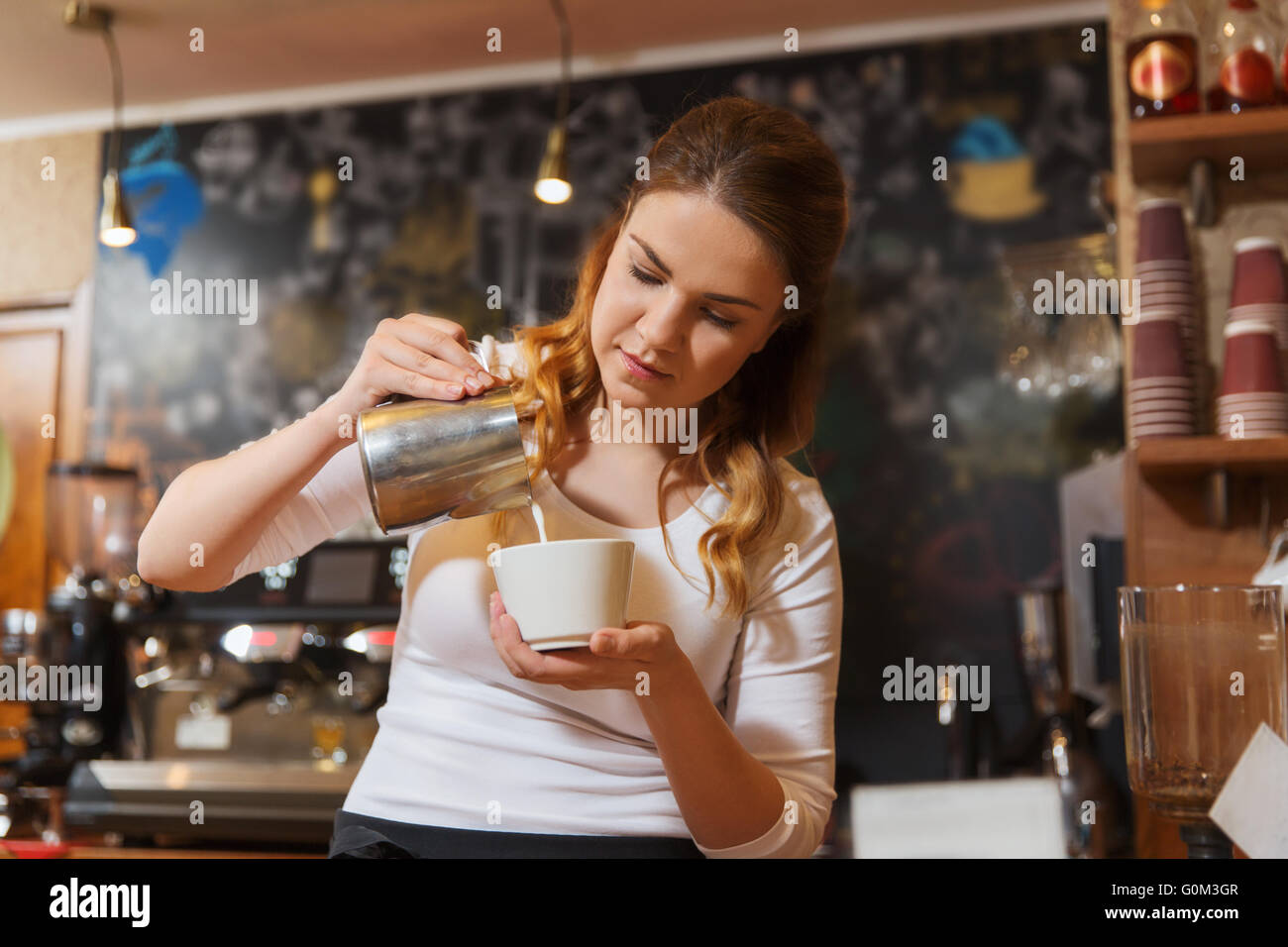 Barista Frau gießt Sahne, Kaffeehaus Stockfoto