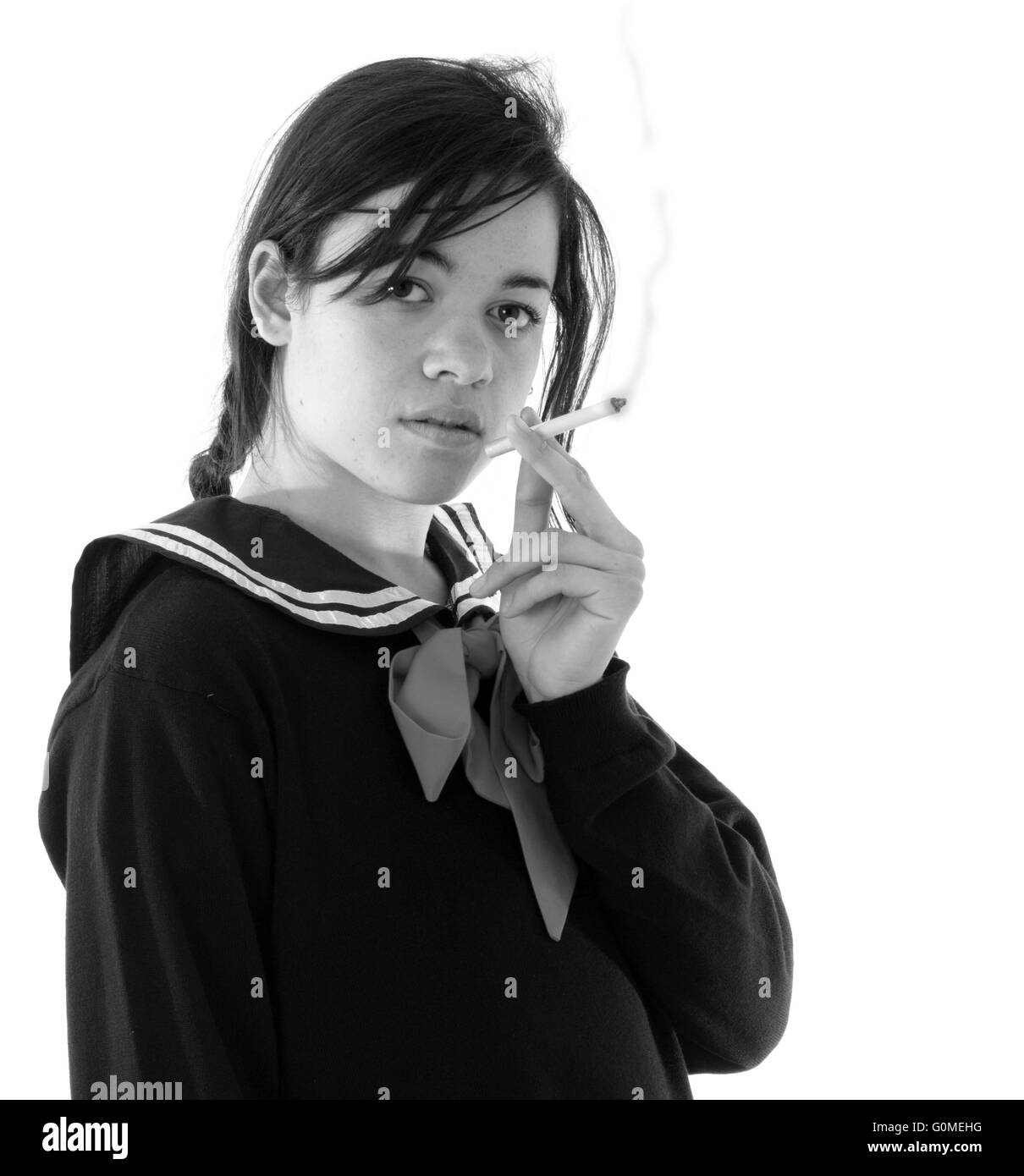 Gemischte Rassen junge Frau wie ein Schulmädchen in japanischem Stil Uniform raucht eine Zigarette. Stockfoto