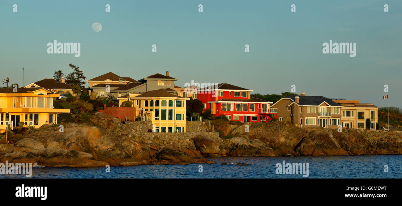 Häuser entlang Esquimalt Meeresküste mit Vollmond steigt bei Sonnenuntergang-Esquimalt, British Columbia, Kanada. Stockfoto