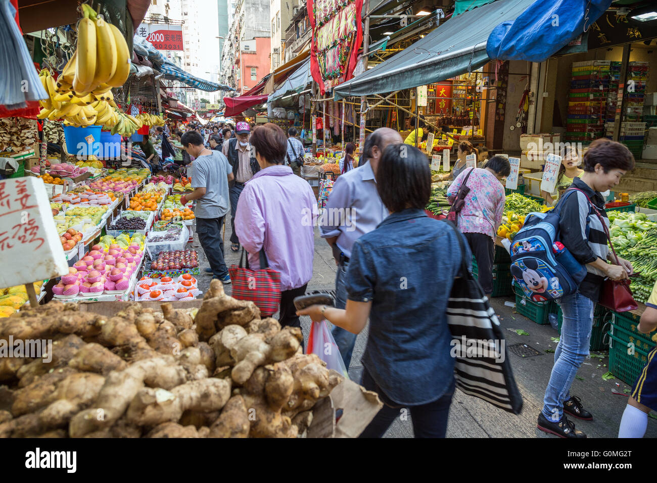 Menschen zwischen den Ständen voller Früchte und Gemüse auf dem Straßenmarkt in Tai Po, Hong Kong, China. Stockfoto