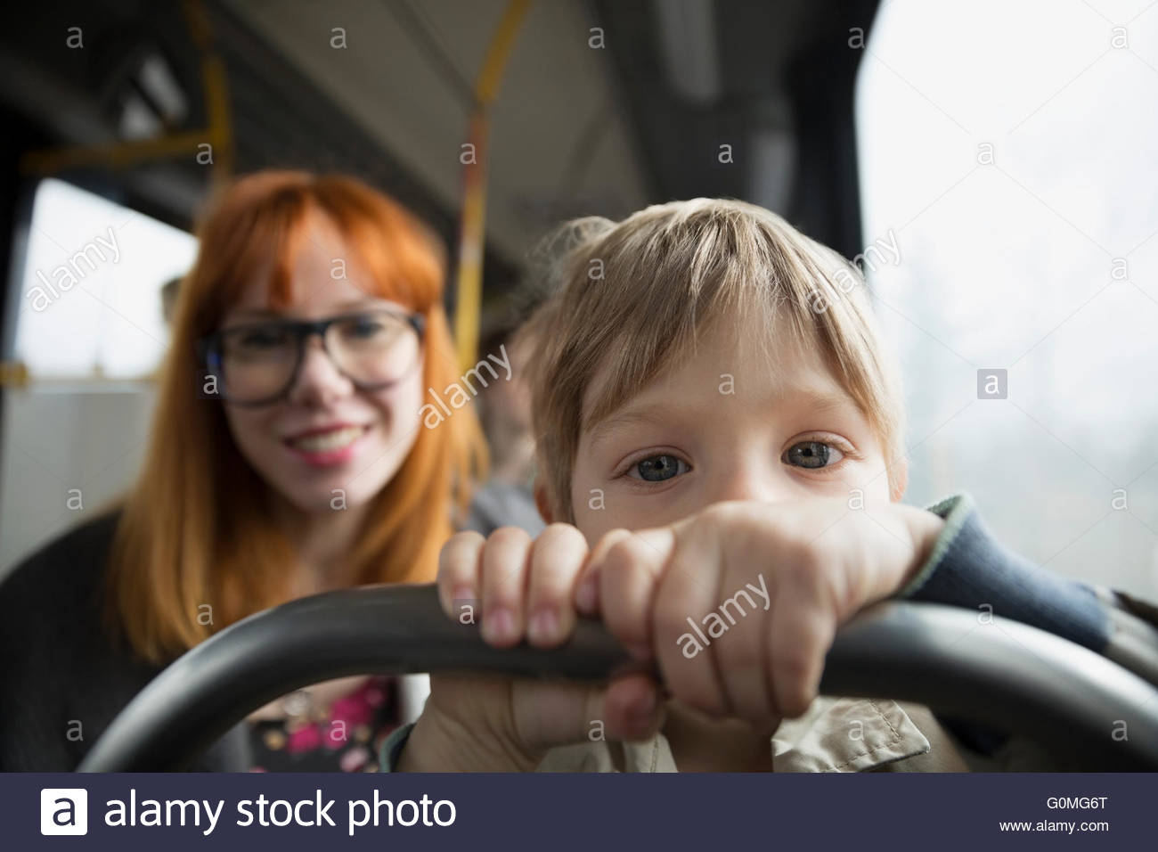 Porträt neugieriger Junge Reiten Bus mit Mutter Stockfoto