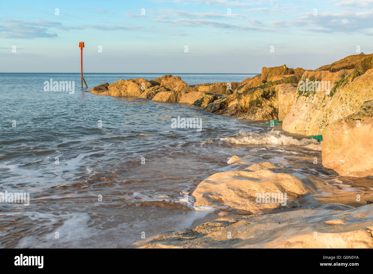 Am frühen Morgen am felsigen Strand von Westbay in England, Bojen mit beruhigende Aufnahmen von der Gefahr-Marker in der frühen Morgensonne Stockfoto