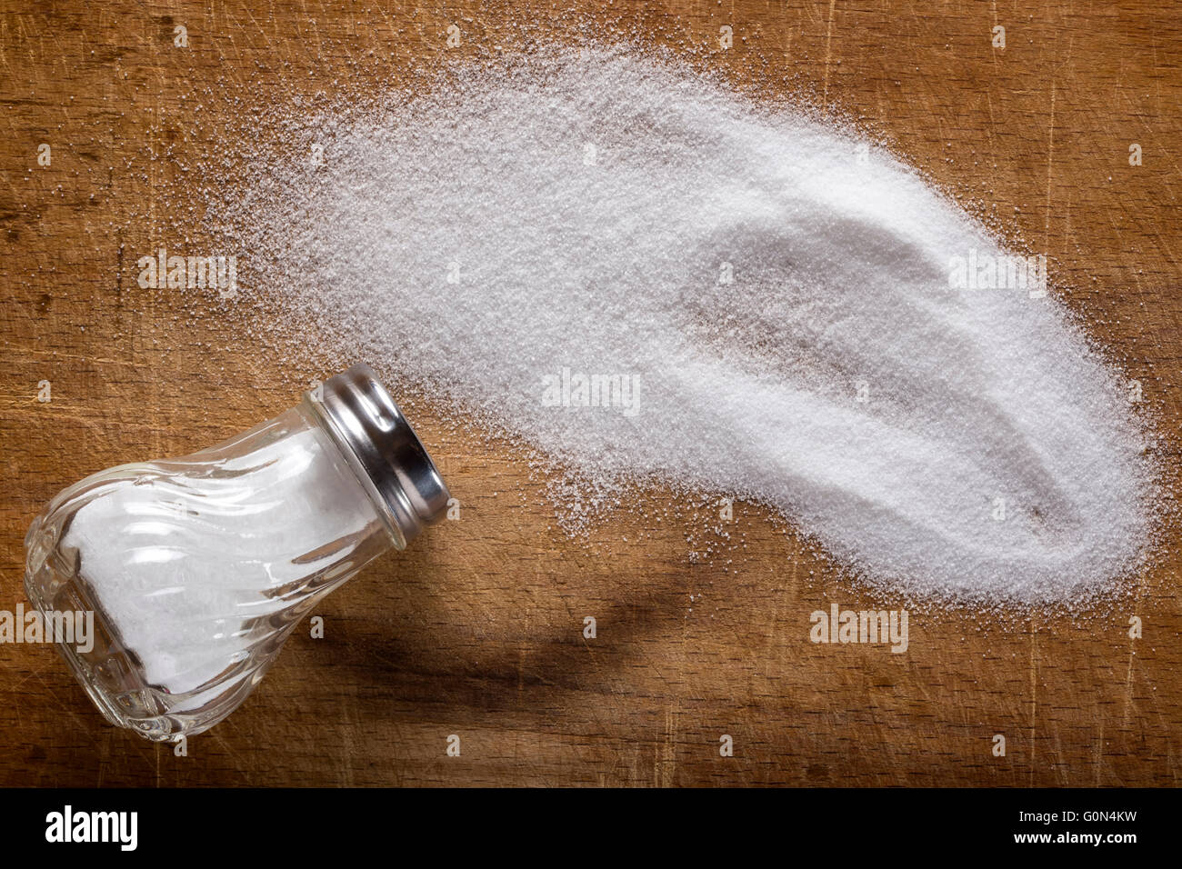 Salz Verschütten auf Holztisch von Salzstreuer Stockfoto