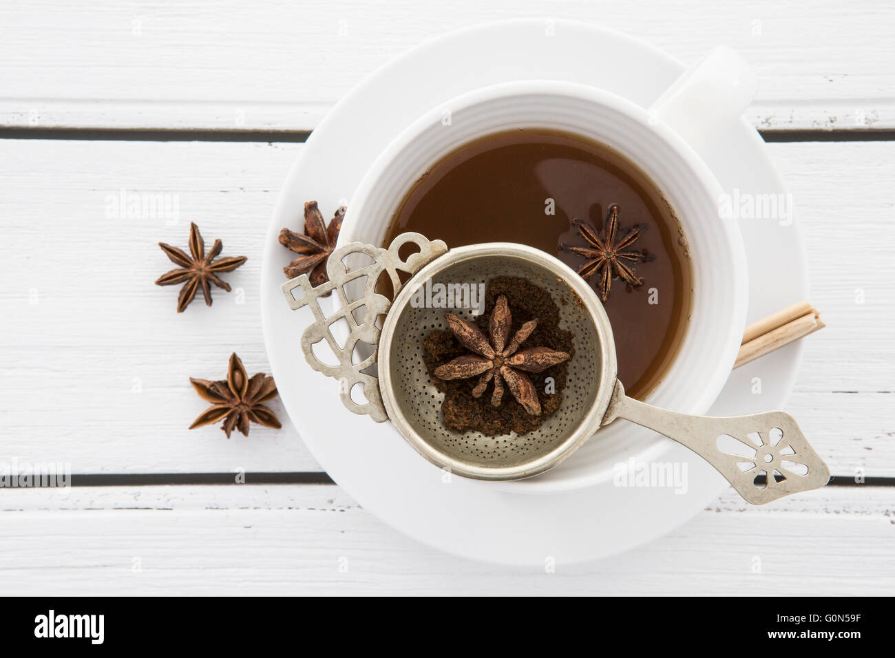 Tasse Tee mit einem Vintage Sieb und Sternanis auf weißem rustikalen hölzernen Hintergrund Stockfoto
