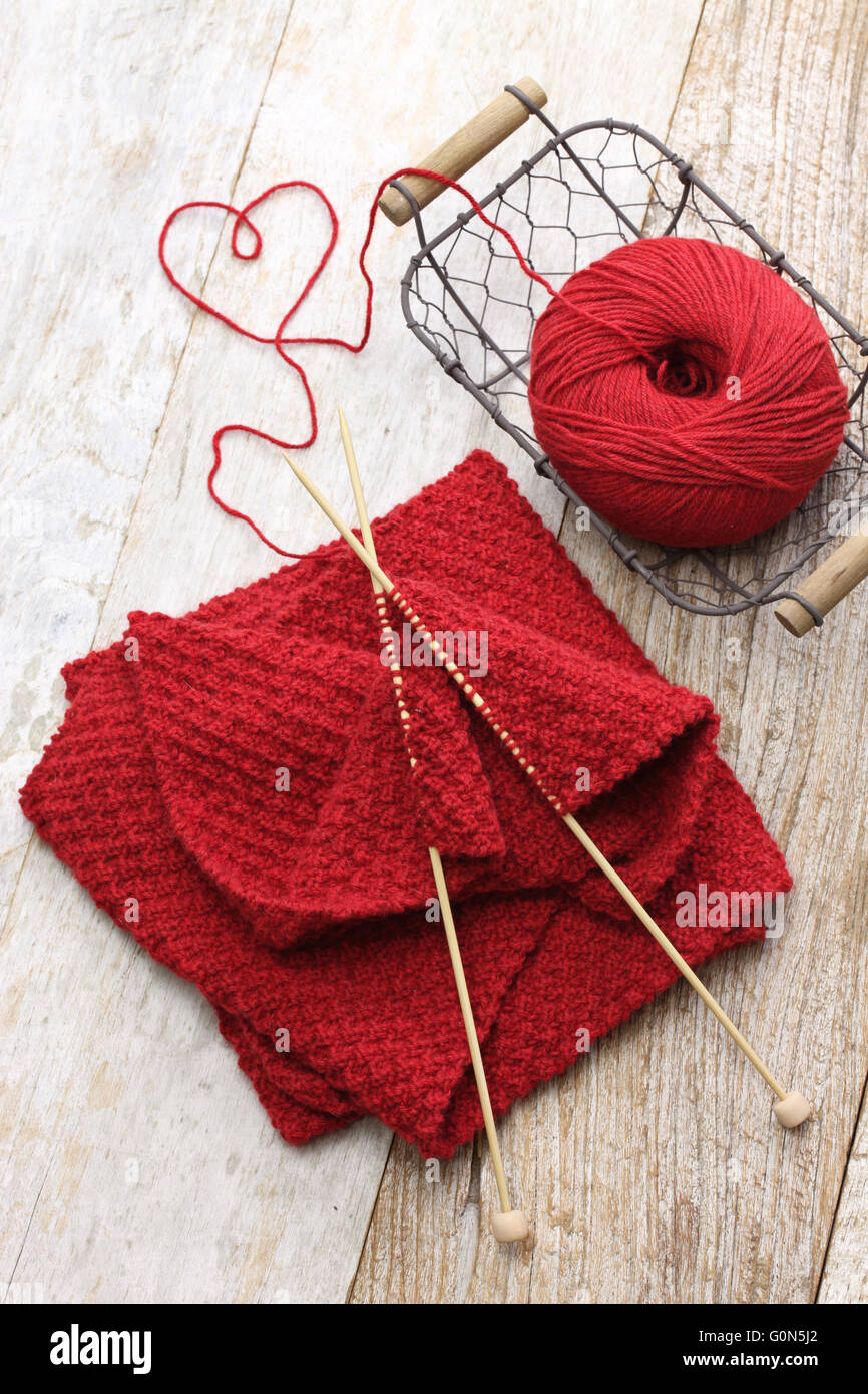 Handgestrickte roten Schal, Knäuel und Stricknadeln, handgemachte Weihnachtsgeschenk Stockfoto