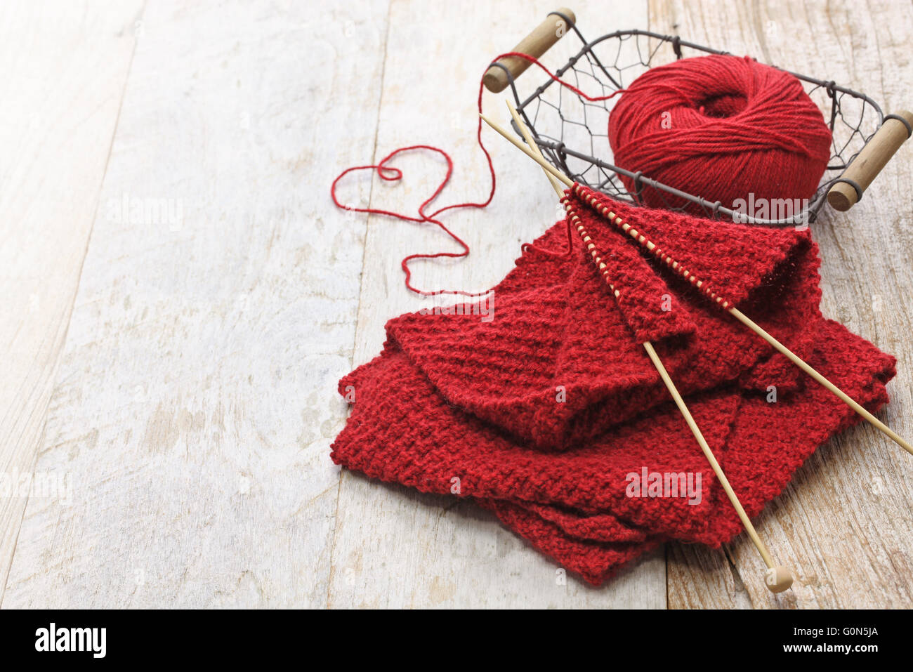 Handgestrickte roten Schal, Knäuel und Stricknadeln, handgemachte Weihnachtsgeschenk Stockfoto