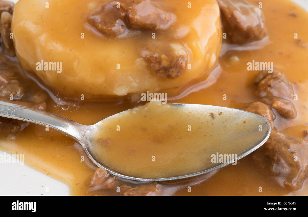Nahaufnahme der gestampften Kartoffeln in Sauce mit Rind Tipps TV Dinner mit einem Löffel auf einem Teller. Stockfoto
