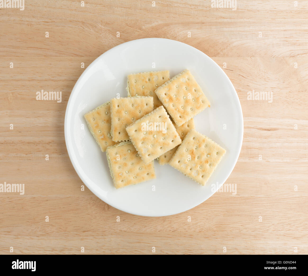 Draufsicht der Frischkäse und Schnittlauch Cracker auf einem weißen Teller oben auf einer hölzernen Tischplatte. Stockfoto