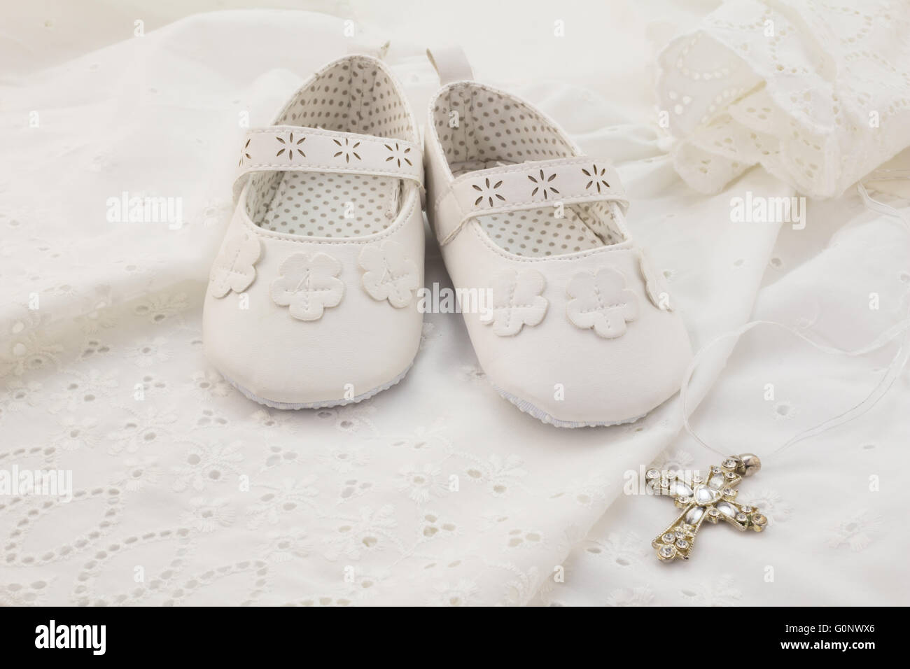 Baby Taufe weiße Schuhe mit Kreuz auf weißer Spitze Hintergrund Stockfoto
