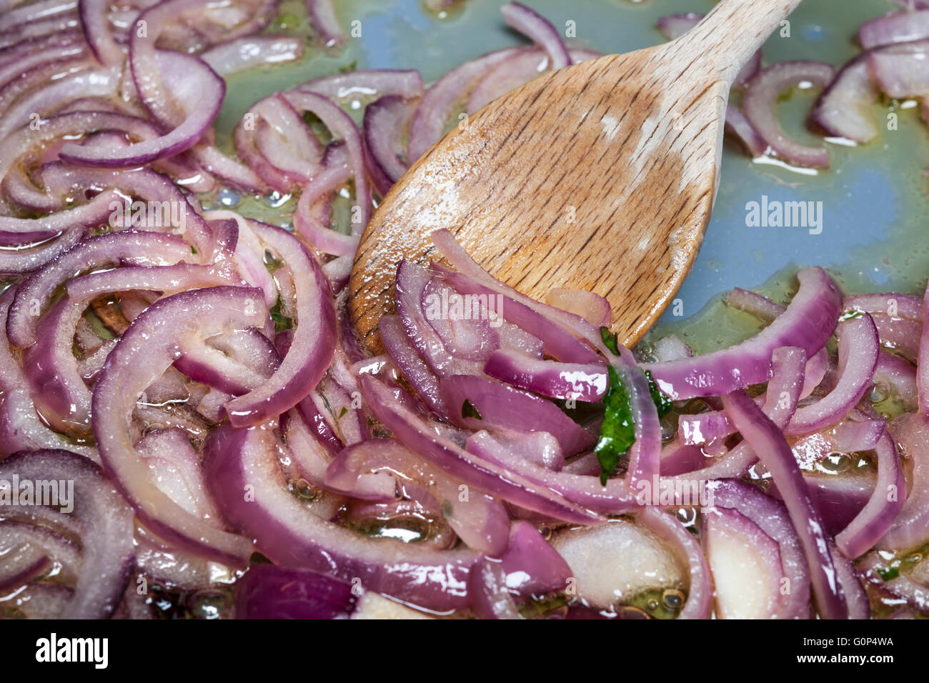 Mitreißende sautieren rote Zwiebeln mit einem Holzlöffel Kochen Pfanne, Nahaufnahme Stockfoto