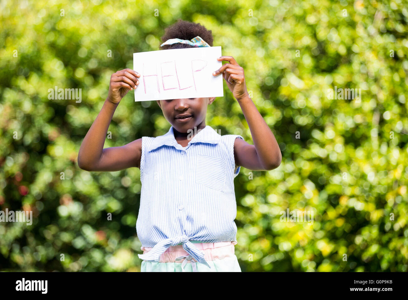 Niedliche Mischenrennen Mädchen hält eine Papier mit Hilfenachricht Stockfoto