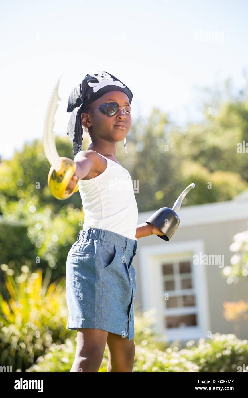 Niedliche Mischenrennen Mädchen Piraten Kleidung tragen und die Kamera mit Kunststoff Schwert Stockfoto