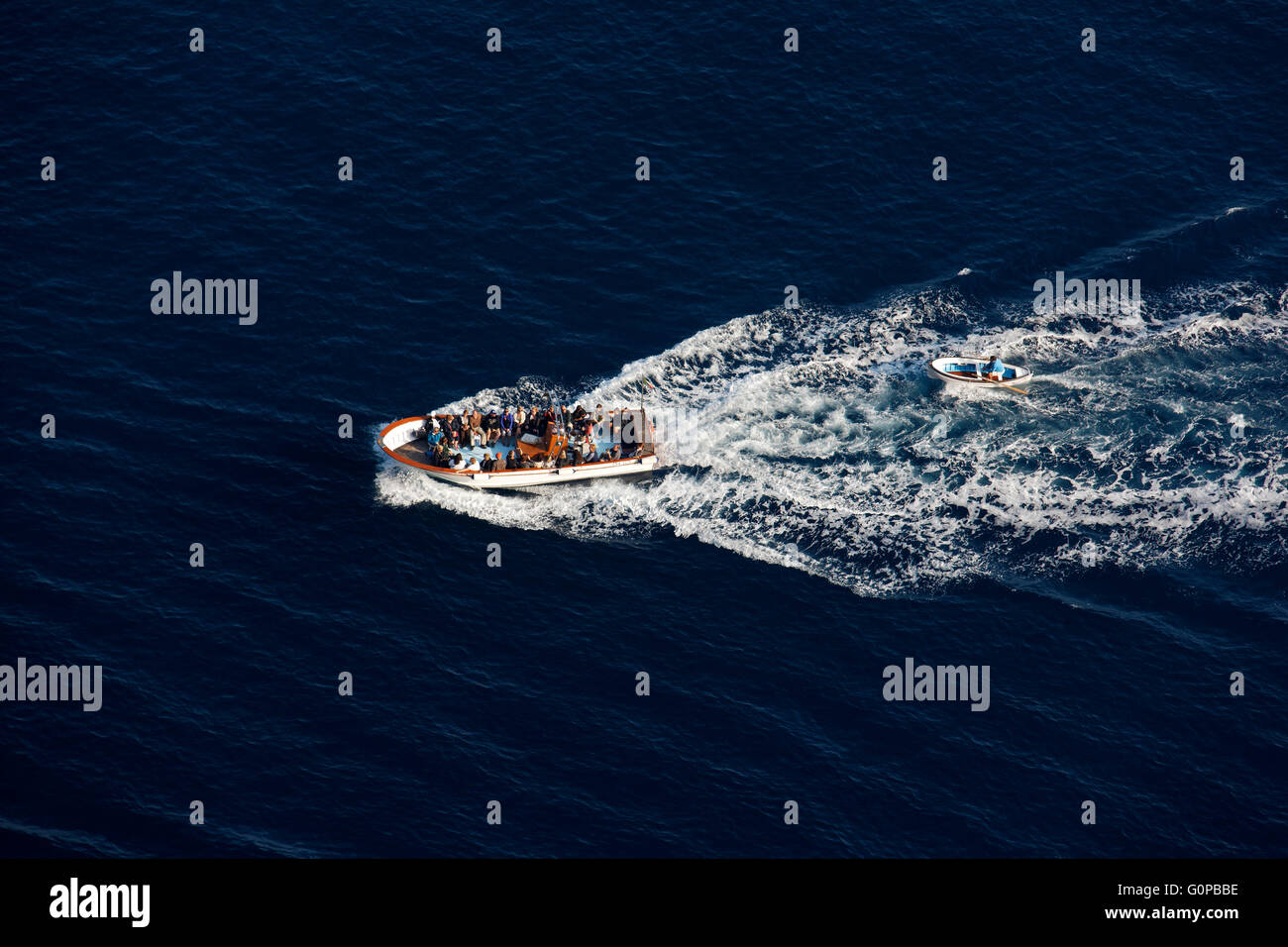 Touristenboot mit Touristen schleppen eine kleine Jolle in der Bucht von Neapel, Capri, Kampanien, Italien, Europa Stockfoto