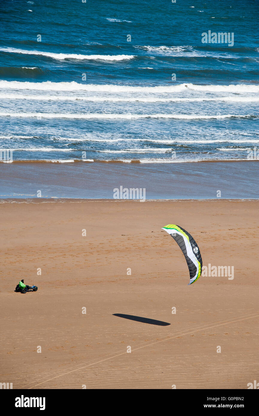 Mann reitet einen Strandbuggy mit Geschwindigkeit mit einem Power-Kite am Strand von Saltburn Nutzung der Windenergie auf Sand am Meer Stockfoto
