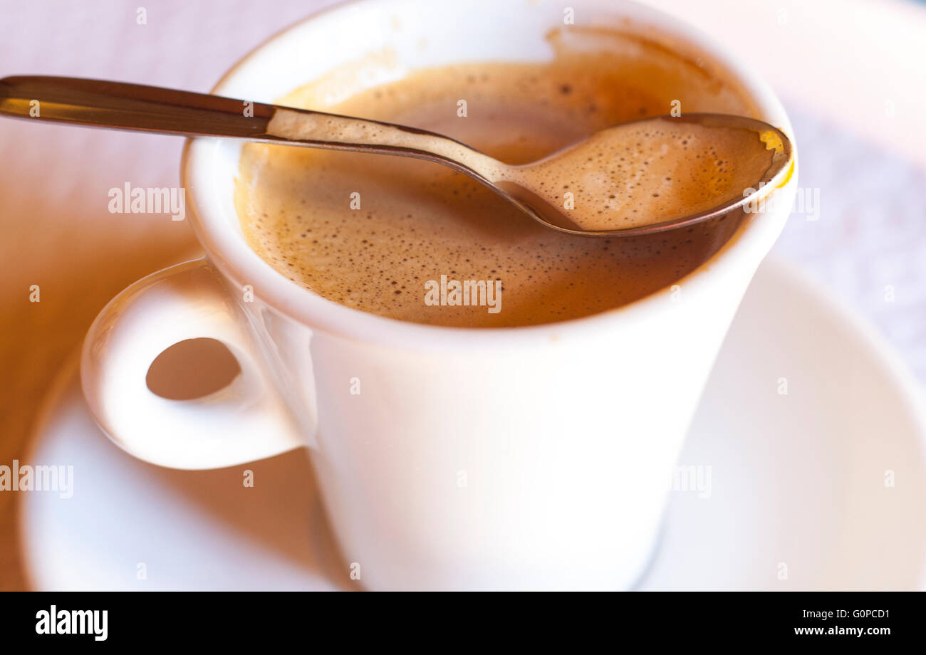 Tasse frischen Kaffee und Milch mit dem Löffel über dem Rand Stockfoto