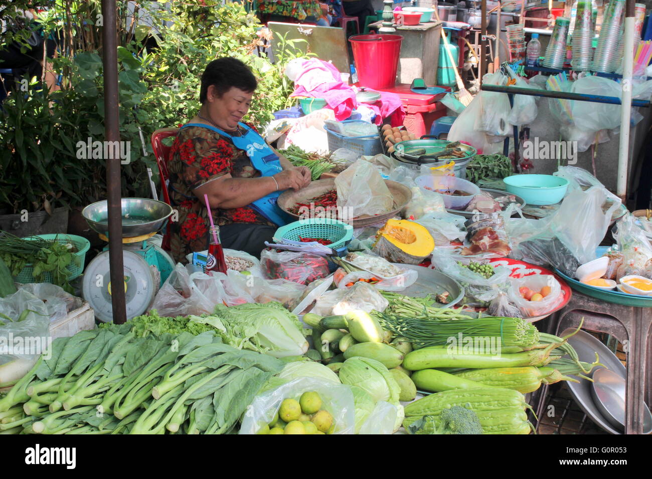 Frisches Obst und Gemüse Stall in Bangkok. Die Frauen sortieren die Chilis beim warten auf Kunden. Stockfoto