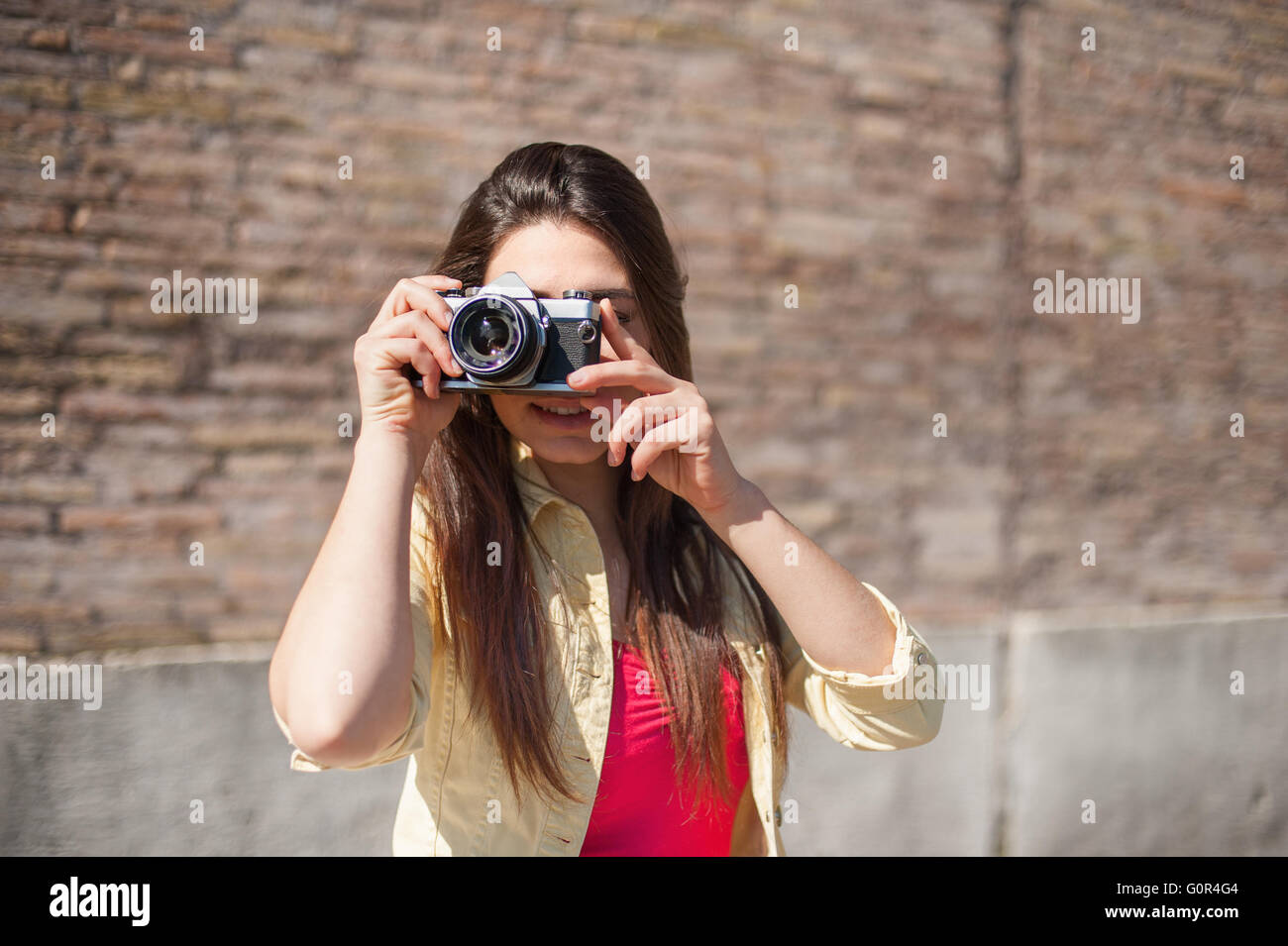 Junge Frau unter Bild im Freien mit Wand im Hintergrund Stockfoto