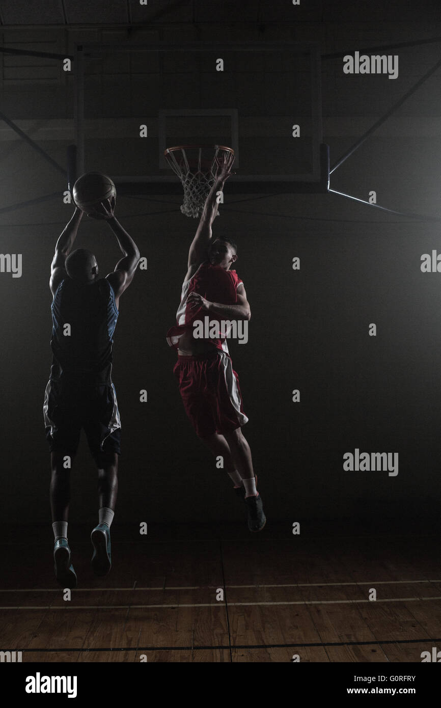 Basketball-Spieler schießen einen Basketball mit einem Verteidiger Stockfoto