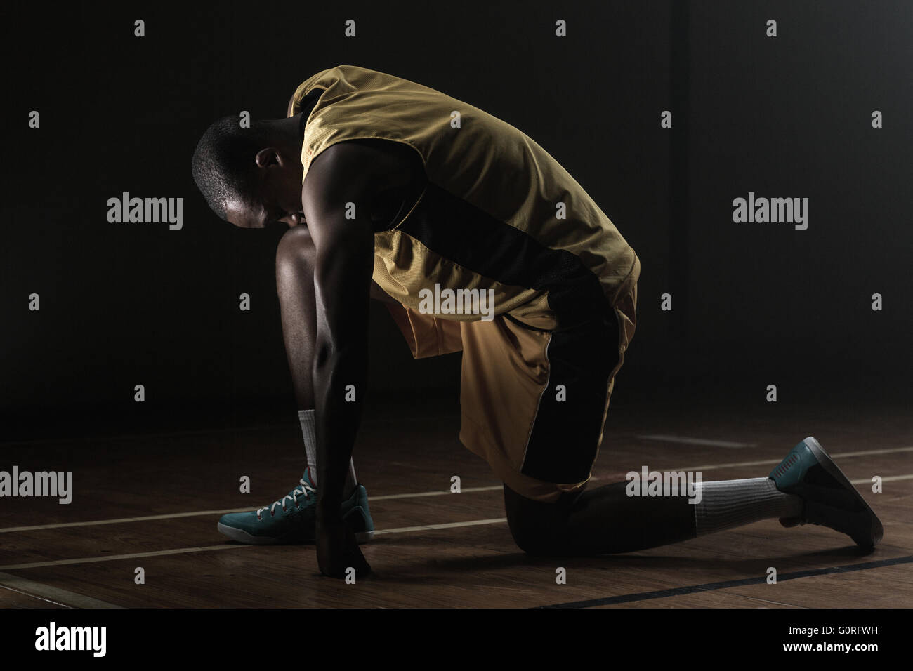 Basketballspieler Vorbereitung zu spielen mit Knie auf dem Boden und den Kopf gesenkt Stockfoto
