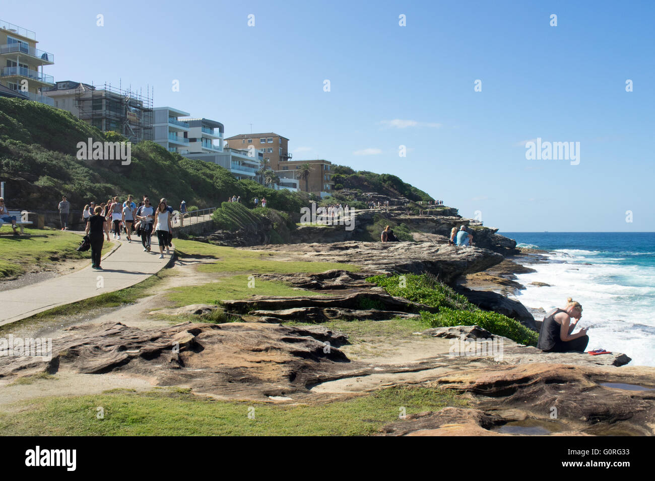 Menschen zu Fuß entlang Sydneys Coastal Walk in Tamarama mit Blick auf den Pazifischen Ozean. Stockfoto