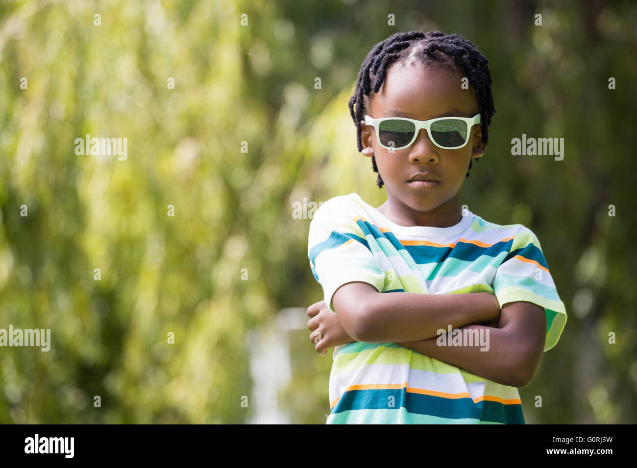 Ein Kind mit einer Sonnenbrille, die seine Arme kreuzen Stockfoto
