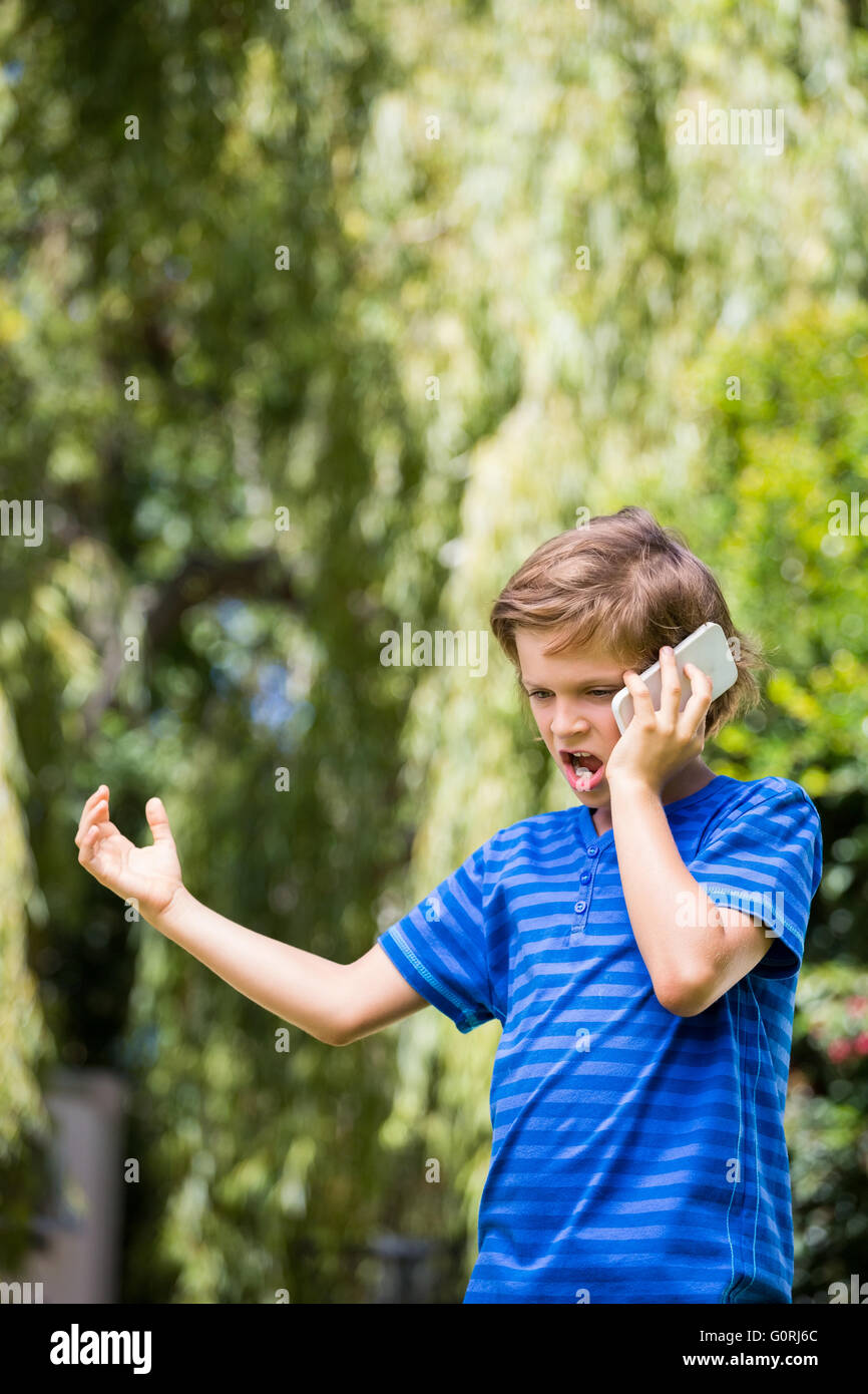 Ein kleiner Junge ist wütend auf seinem Handy Stockfoto