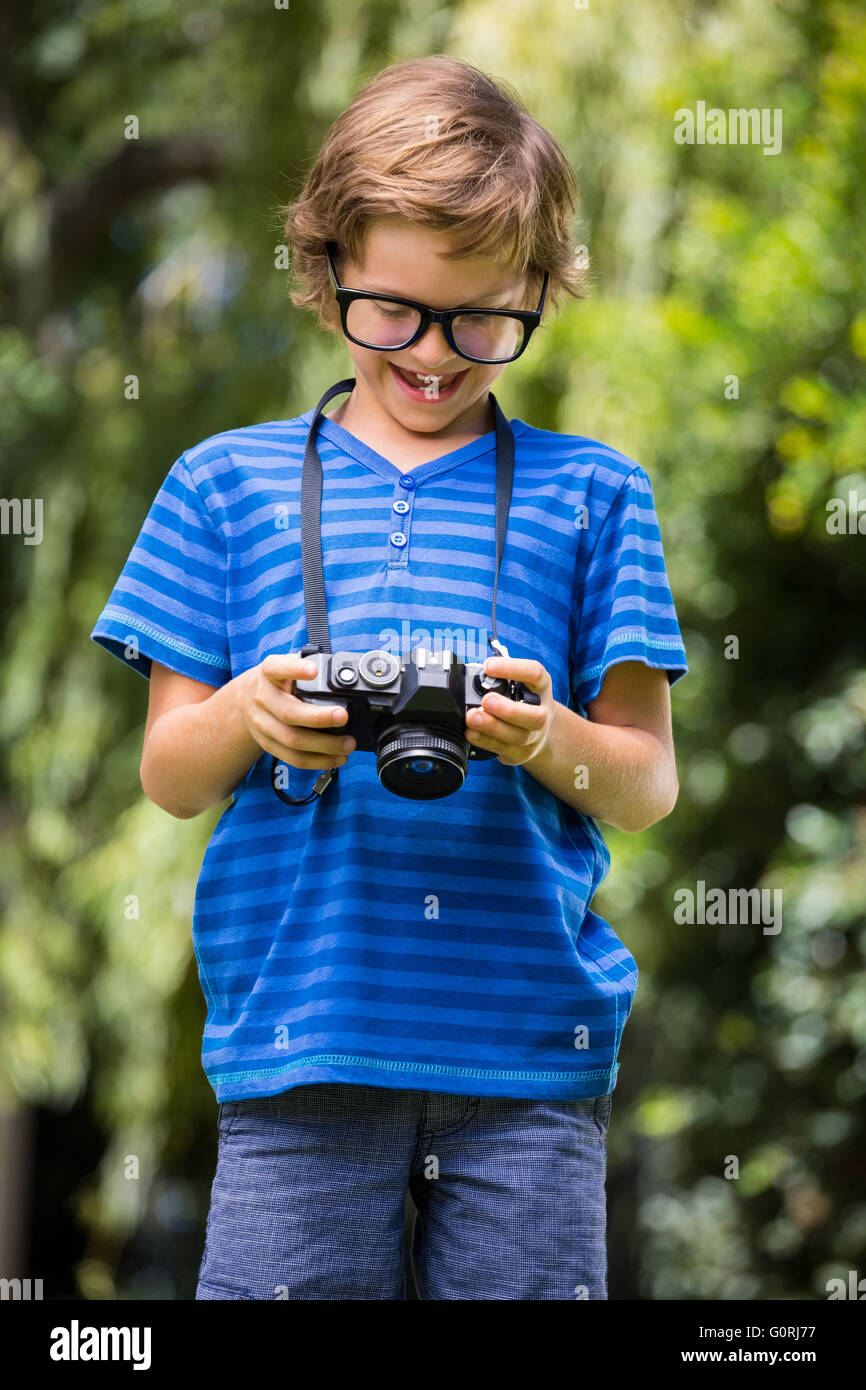Netter Junge mit Brille hält und auf der Suche nach einer Kamera Stockfoto