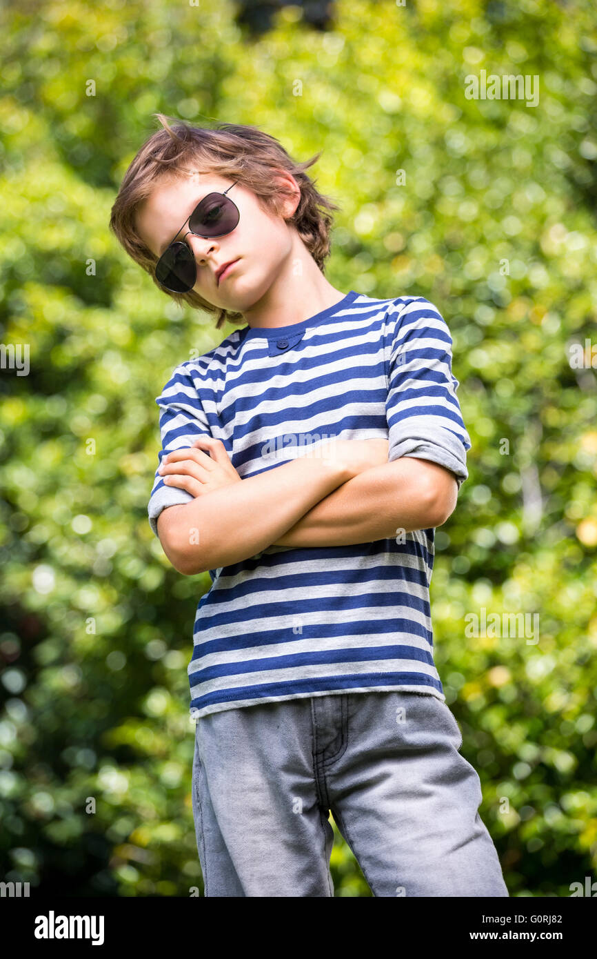 Süsser Boy mit Sonnenbrille posiert mit verschränkten Armen Stockfoto