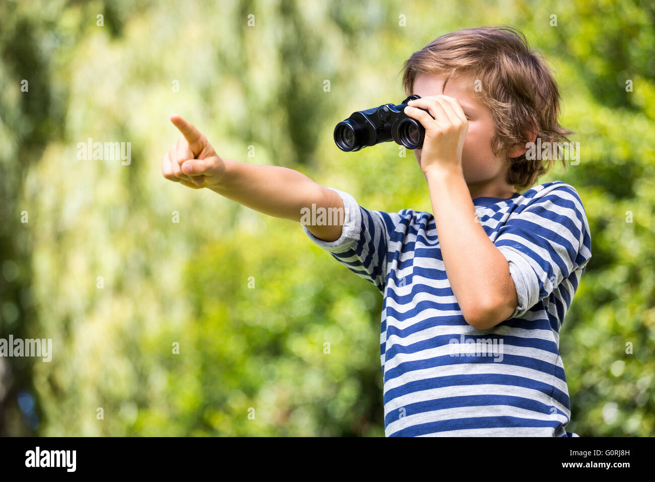 Porträt von süsser Boy mit dem Fernglas suchen und etwas zeigen Stockfoto