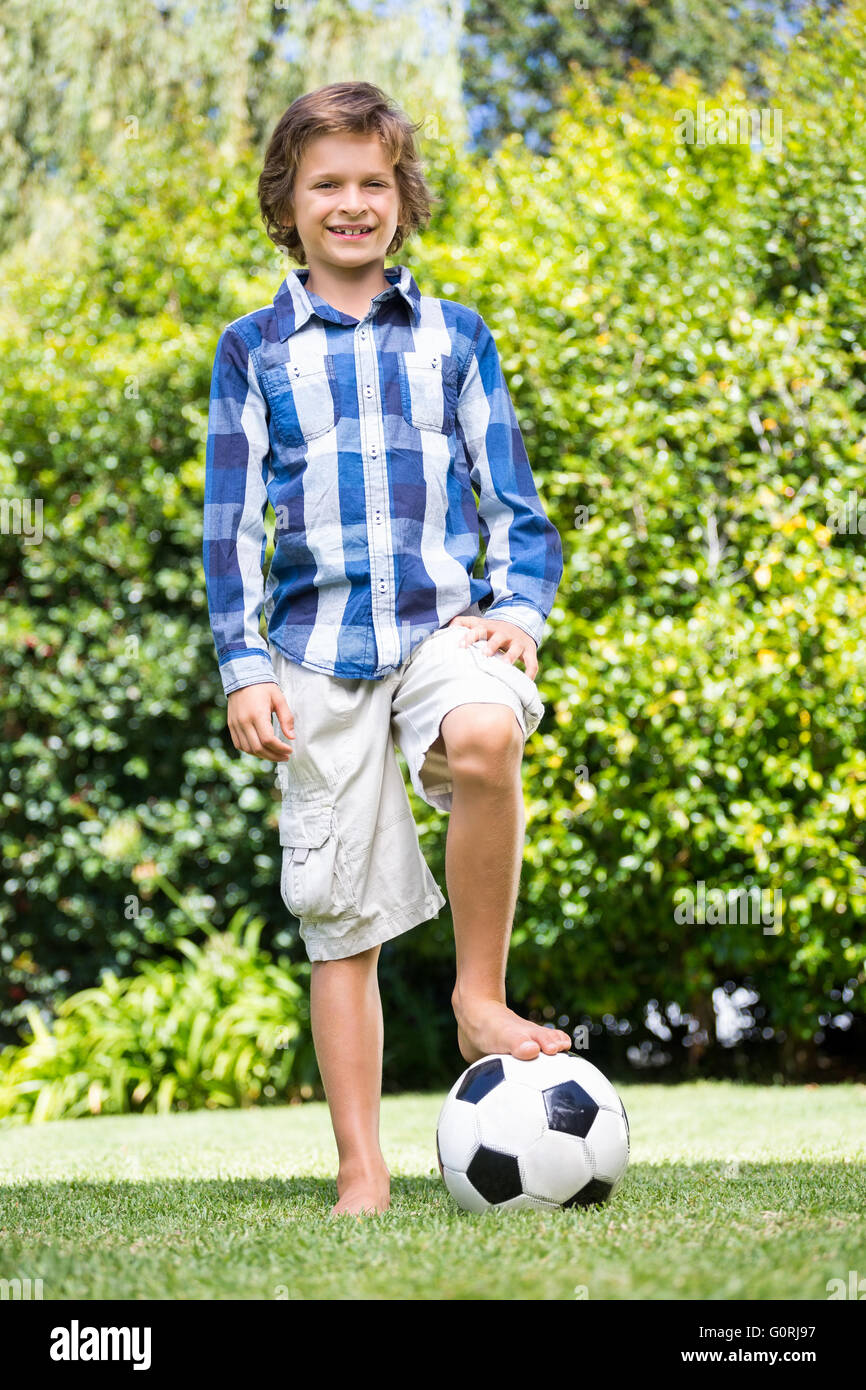 Süsser Boy Lächeln und posieren mit seinem Fuß auf einem Fußball Stockfoto