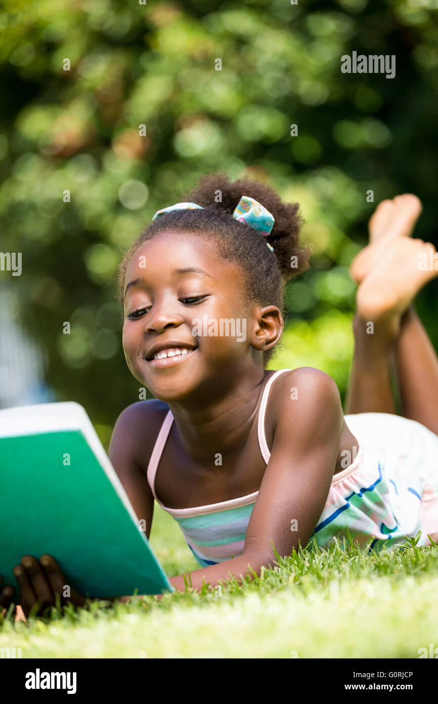 Lächelnde niedliche Mischenrennen Mädchen liegen und ein Buch zu lesen Stockfoto