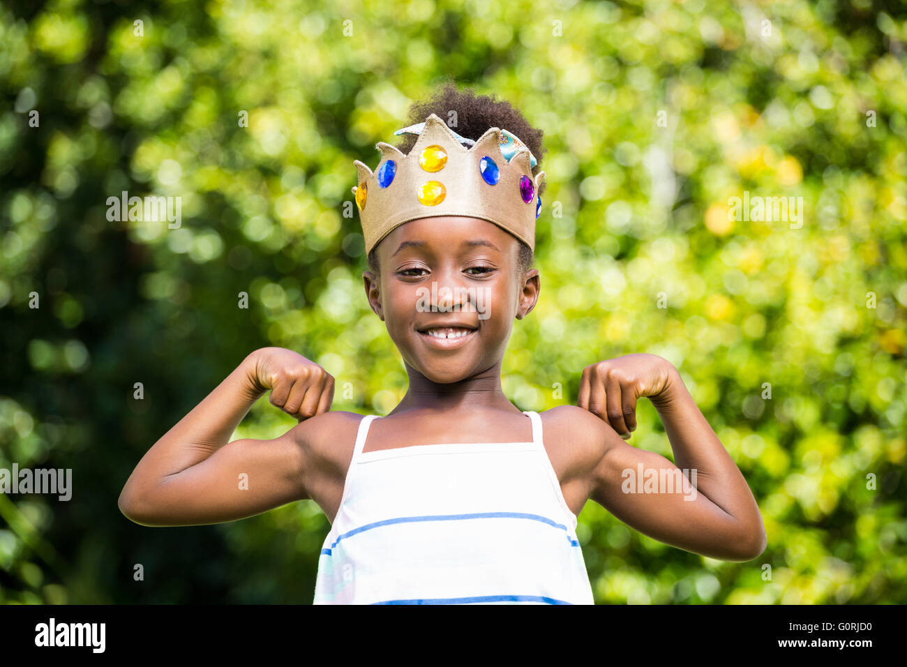 Niedliche Mischenrennen Mädchen hält eine Krone und zeigt ihren Bizeps Stockfoto