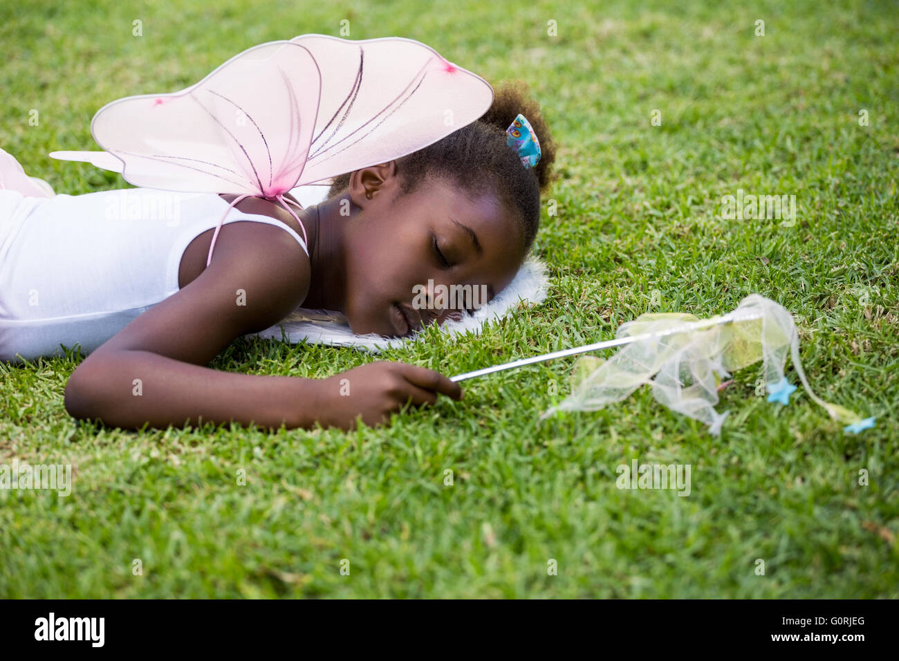 Niedliche Mischenrennen Mädchen Fee Kleid und schlafen auf dem Rasen Stockfoto