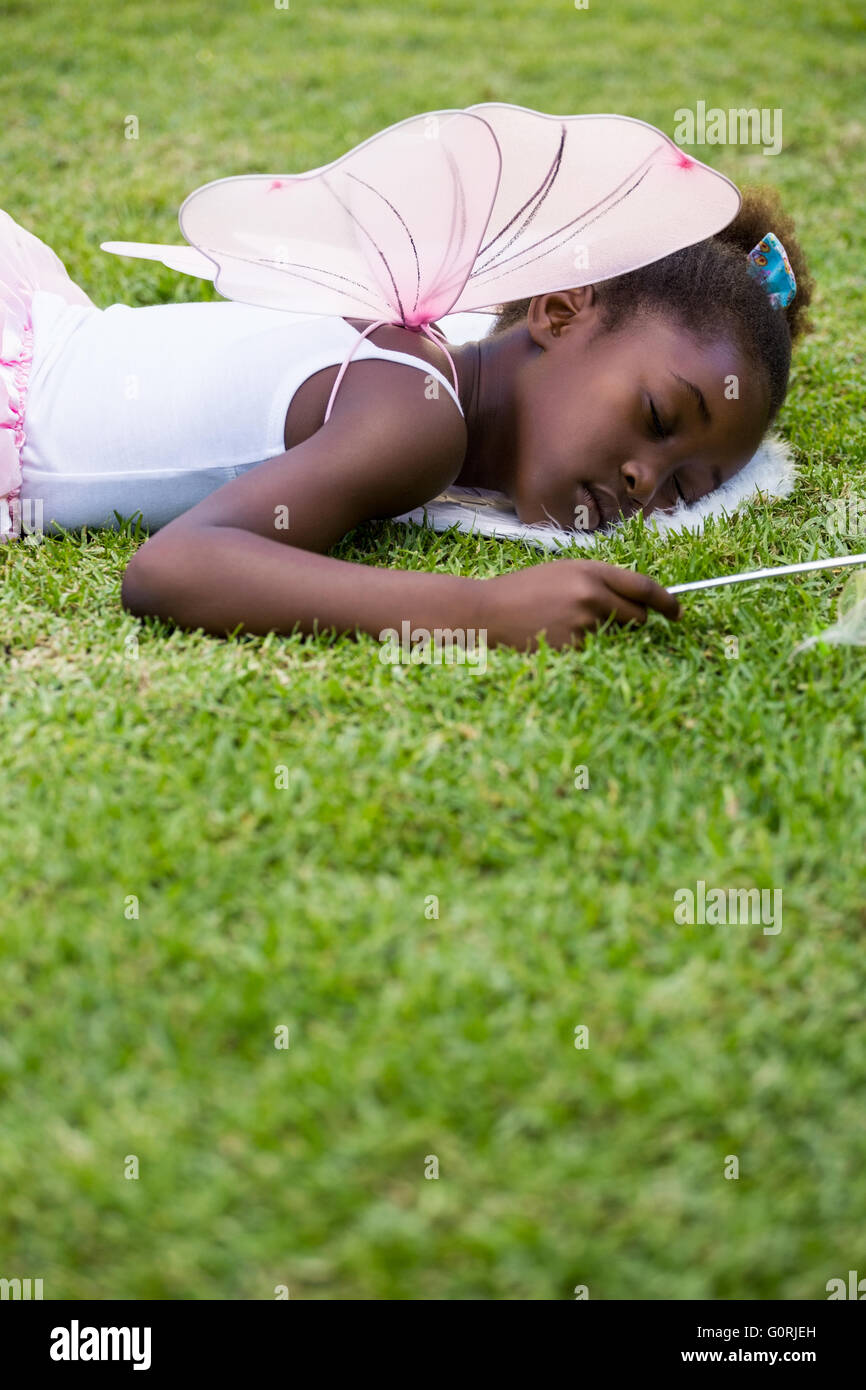 Niedliche Mischenrennen Mädchen Fee Kleid und schlafen auf dem Rasen Stockfoto