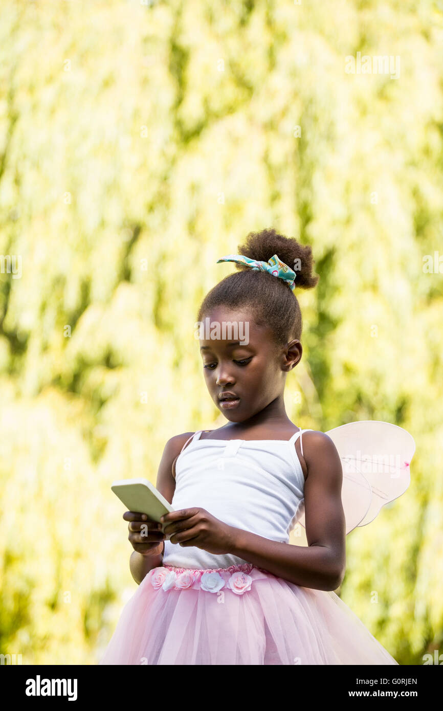 Niedliche Mischenrennen Mädchen Fee Kleid und per smartphone Stockfoto