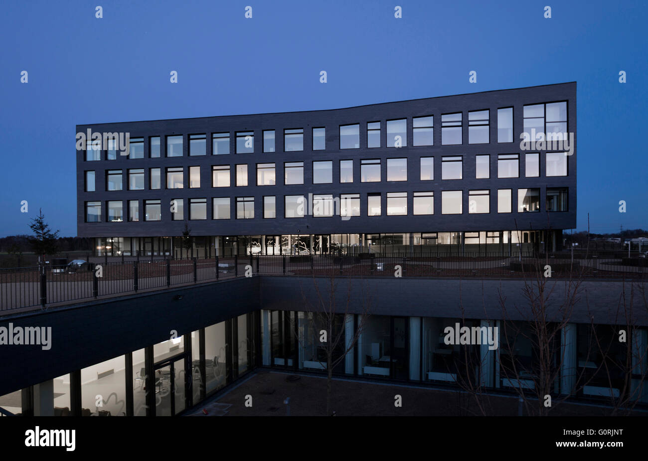 Rathaus und Gesundheitszentrum, Egedal, Dänemark. Außenansicht des Gebäudes in der Nacht. Niedriger Stufe Büros im Blick. Stockfoto