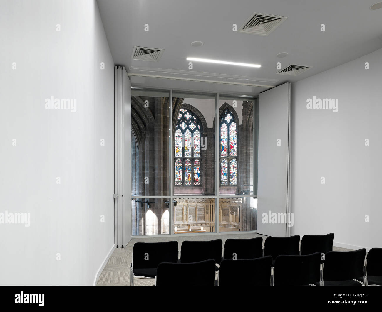 Alle Seelen, Bolton, England. Weißer Raum mit Stuhlreihen. Farbige Glasfenster. Stockfoto